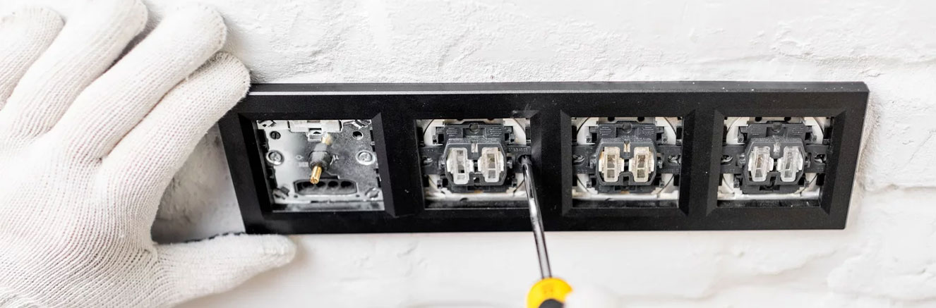 KAD Electricians team installing a smart light switch on a wall, connecting the electrical wiring carefully.